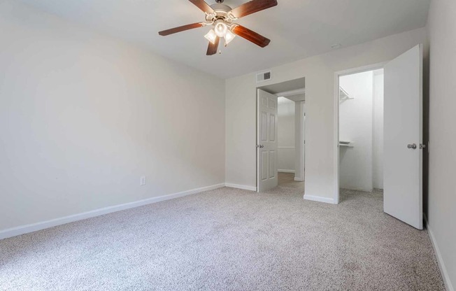A room with a ceiling fan and carpeted floor.