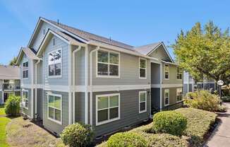 A grey house with a white trim and a brown roof.
