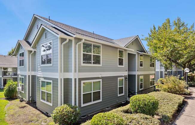 A grey house with a white trim and a brown roof.