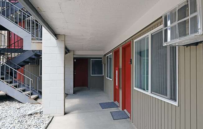 A long hallway with red doors and a metal staircase.