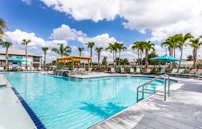 exterior pool with patio furniture and palm trees on sunny day