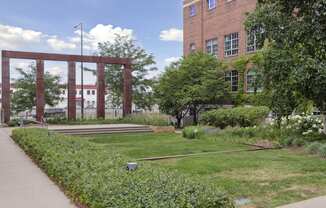 a grassy area in front of a brick building with a large wooden structure in the background