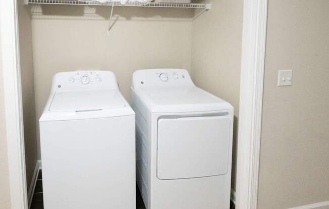 Two white front loading washing machines in a small laundry room.