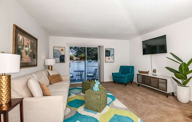 a living room with a couch and a tv and a door to a balcony