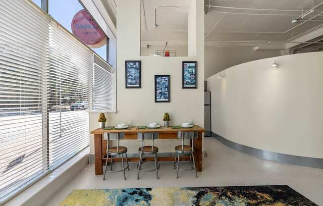 A dining room with a table set for two and a rug on the floor.