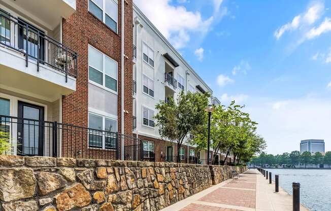 A row of modern apartment buildings line a waterfront walkway.