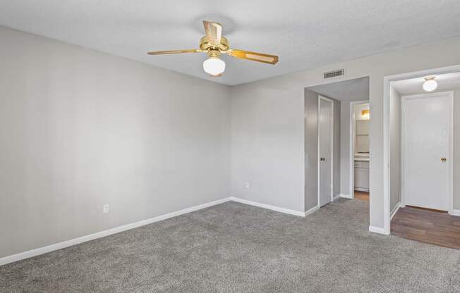 A room with a ceiling fan and carpeted floor.