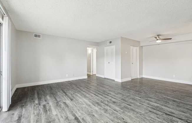 A room with a ceiling fan and wood flooring.