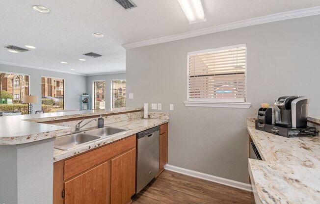 A kitchen with a marble countertop and wooden cabinets.