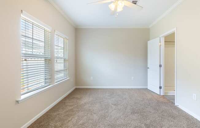 an empty room with a large window and a ceiling fan