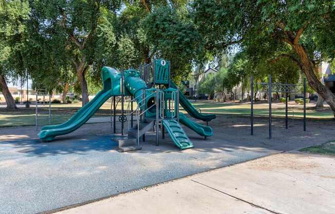 A playground with a green slide and a climbing structure.