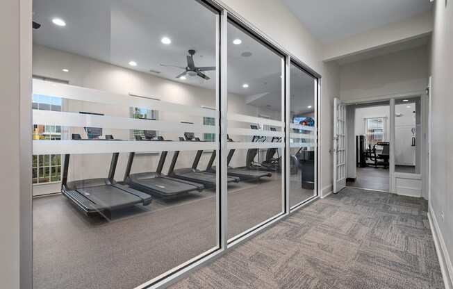 A gym with treadmills and mirrors on the wall.
