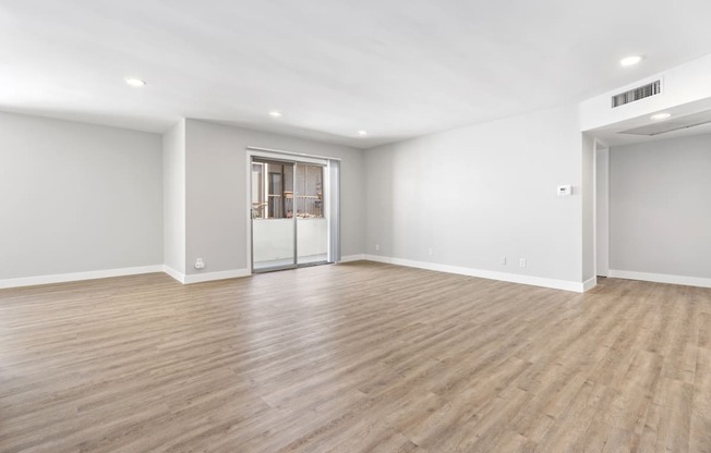 an empty living room with white walls and wood flooring