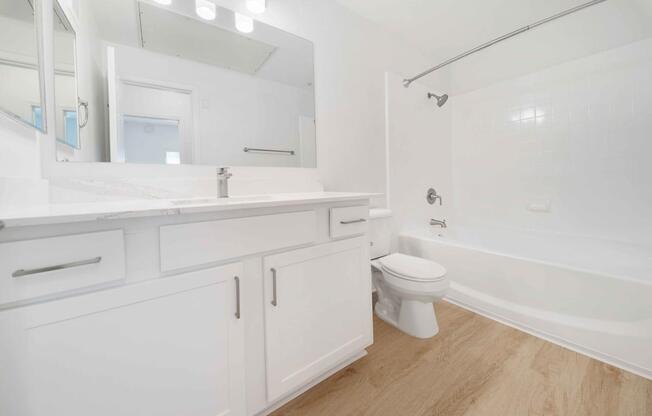 A white bathroom with a toilet, sink, and bathtub.
