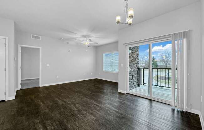an empty living room with a sliding glass door to a balcony