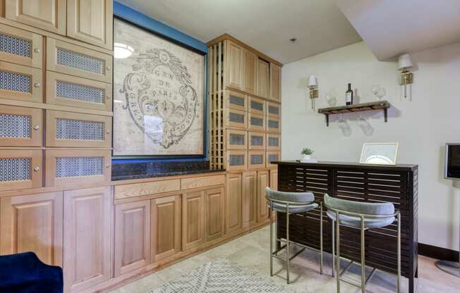 a bar with three stools in a room with wooden cabinets