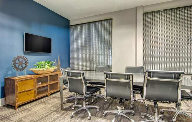 a conference room with a table and chairs and a tv on the wall