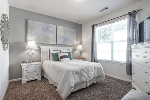 A bedroom with a large bed and two lamps.