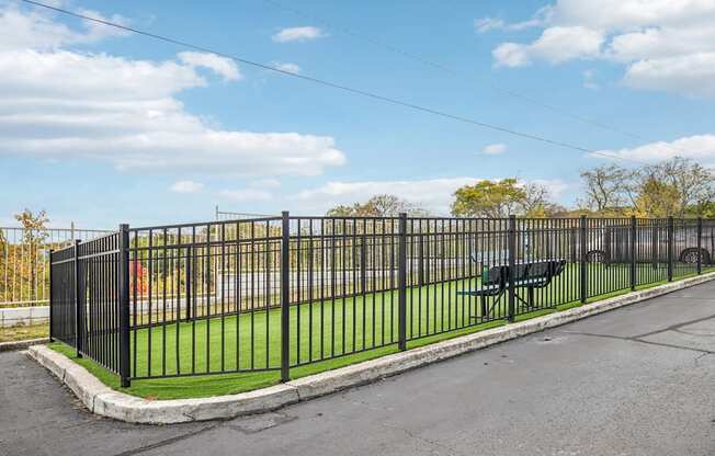 A black metal fence surrounds a green area.