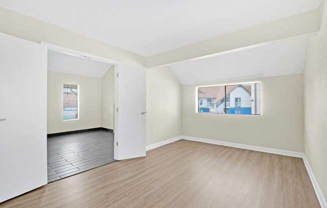 a spacious living room with wood flooring and white walls