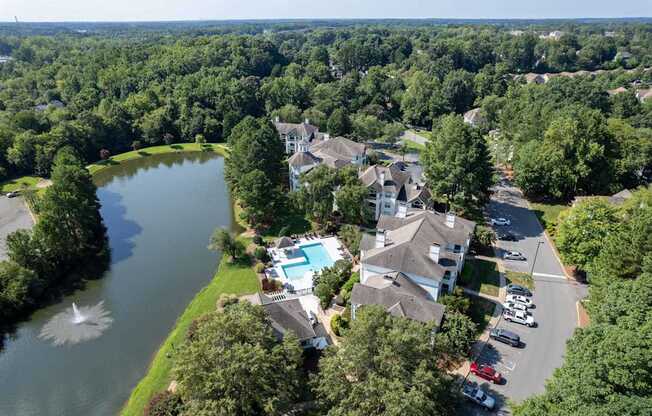 A bird's eye view of a residential area with a lake and a swimming pool.