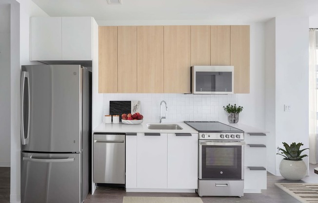 A modern kitchen with a refrigerator, microwave, oven, and sink.