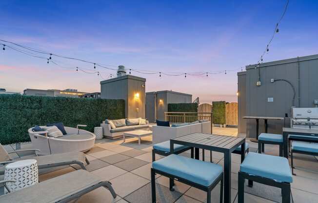 a rooftop patio with tables and chairs and a fire pit