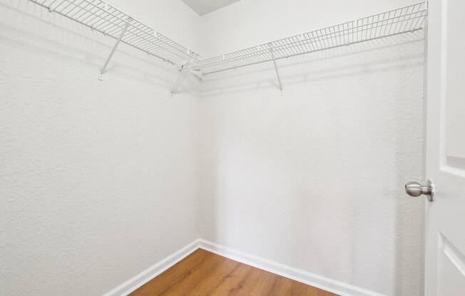 A white wall with a door and a wire shelf.