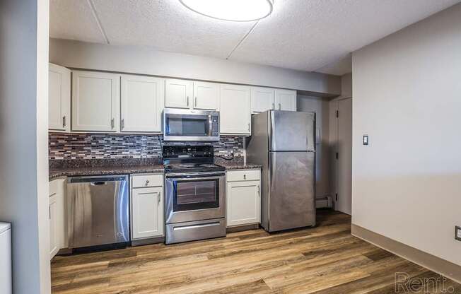 A kitchen with stainless steel appliances and wooden floors.