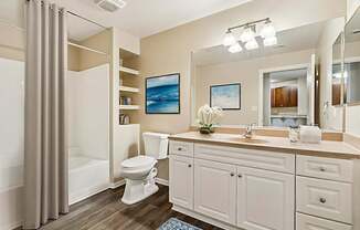 A bathroom with a white toilet, sink, and cabinets.