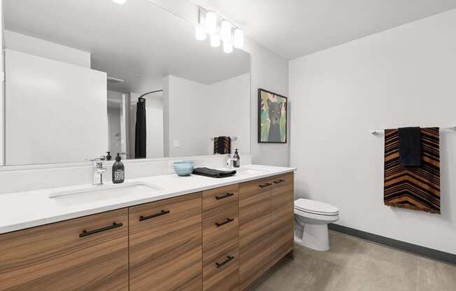 a bathroom with white walls and a wooden vanity with two sinks and a toilet at Ion Town Center, Shoreline, WA 98133