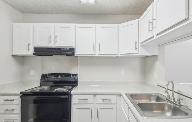 Kitchen with white cabinets and black appliances at Arrowood Crossing Apartments in Charlotte, NC