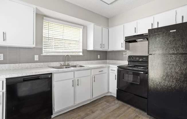 a kitchen with white cabinets and black appliances