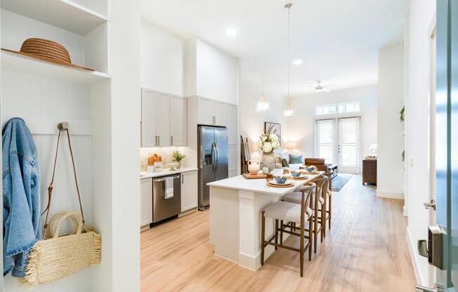 Open entry with built-in mudroom leads into a bright kitchen and living area, where high ceilings and natural light define the flow of the home.
