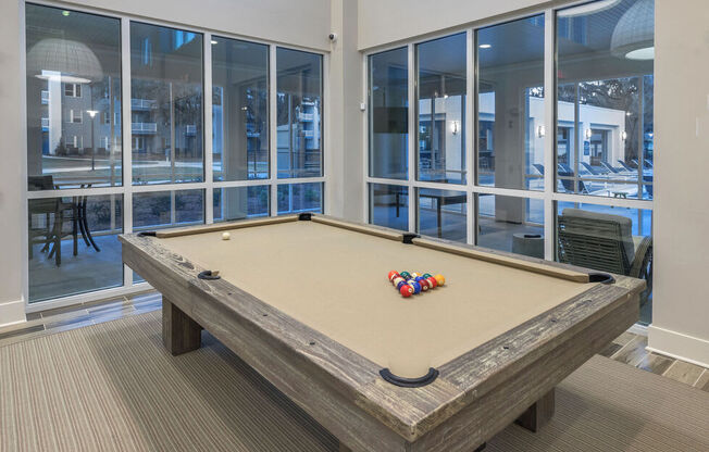 A pool table in a room with a view of the outside.