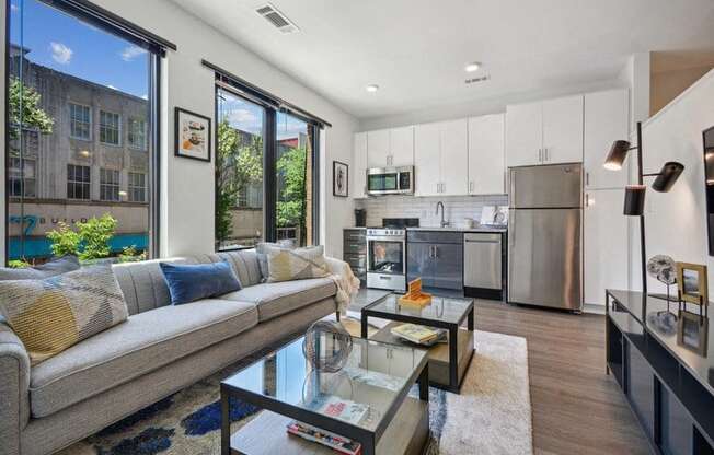 a living room with a couch and a coffee table in front of a kitchen at Link Apartments® 4th Street, Winston-Salem, 27101