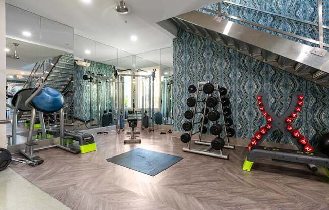 A gym with a variety of equipment including a bench, weights, and a mirror.