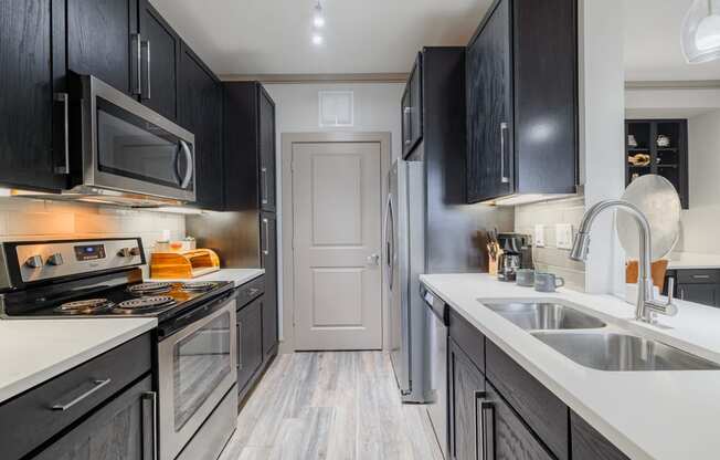 a kitchen with black cabinets and white counter tops and a sink