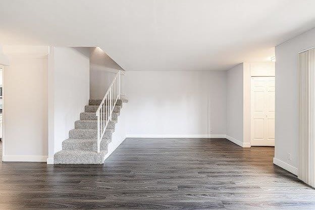 A spacious room with a staircase and wooden flooring.