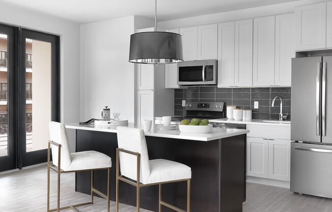 Euclid modern kitchen with white cabinet, stainless steel appliances, island with seating and modern light fixture