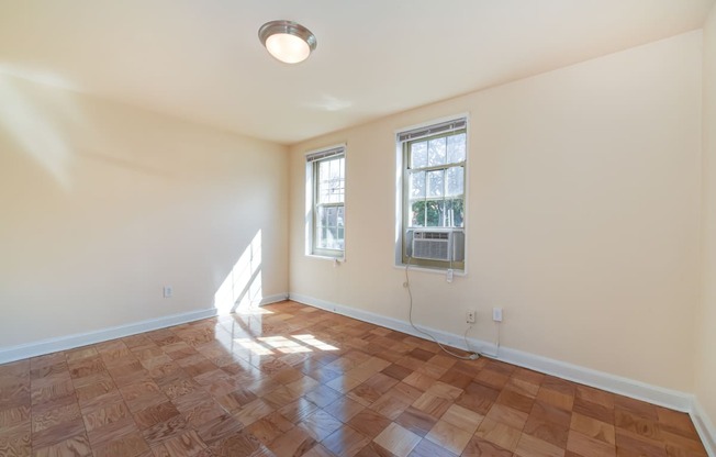 vacant living area with hardwood flooring and large windows at 1401 Sheridan apartments in washington dc