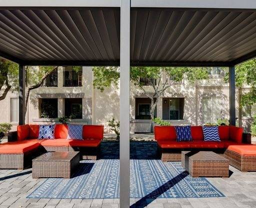 A patio with a red couch and a blue rug.