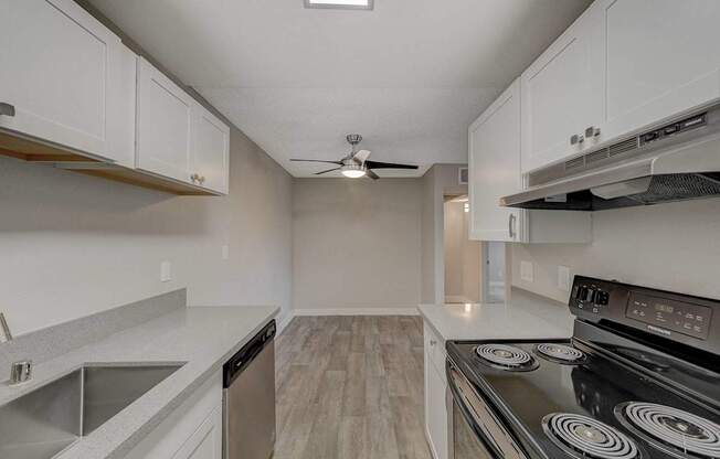 A modern kitchen with a stove, sink, and cabinets.