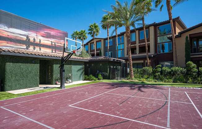 A basketball court is located in front of a building with a large screen showing a basketball game.