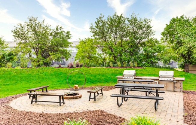 a picnic area with two picnic tables and a grill