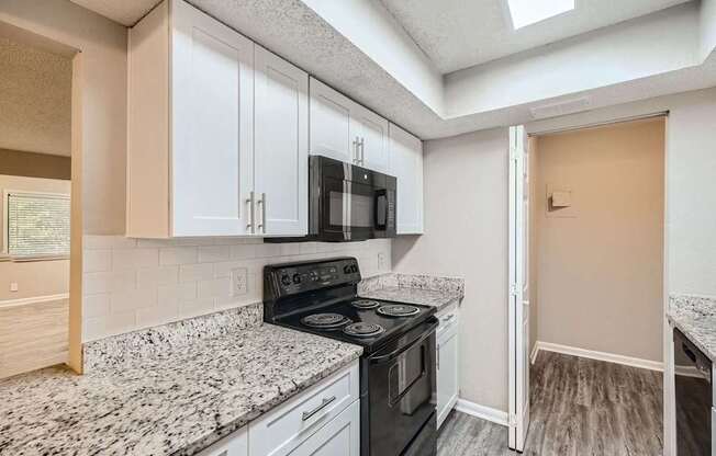 A kitchen with a black stove top oven and white cabinets.