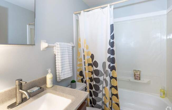 A bathroom with a sink, mirror, and shower.