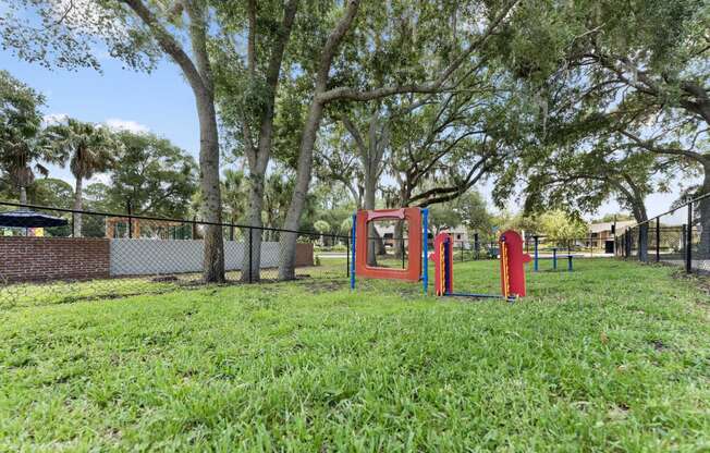 a park with a playground and a fence and trees