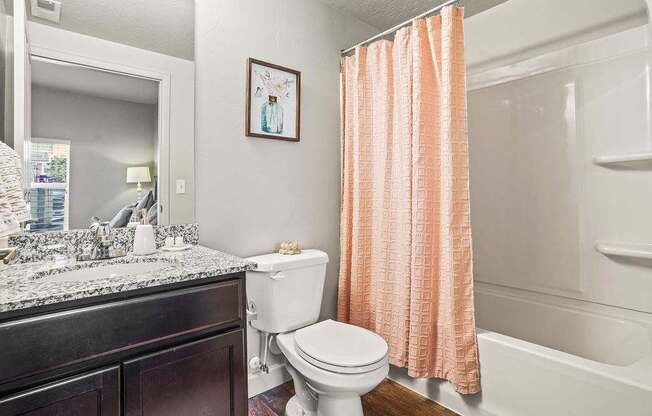 A white toilet sits next to a shower curtain in a bathroom.