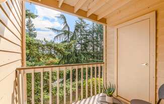 A balcony with a table and chairs overlooking a forest.
